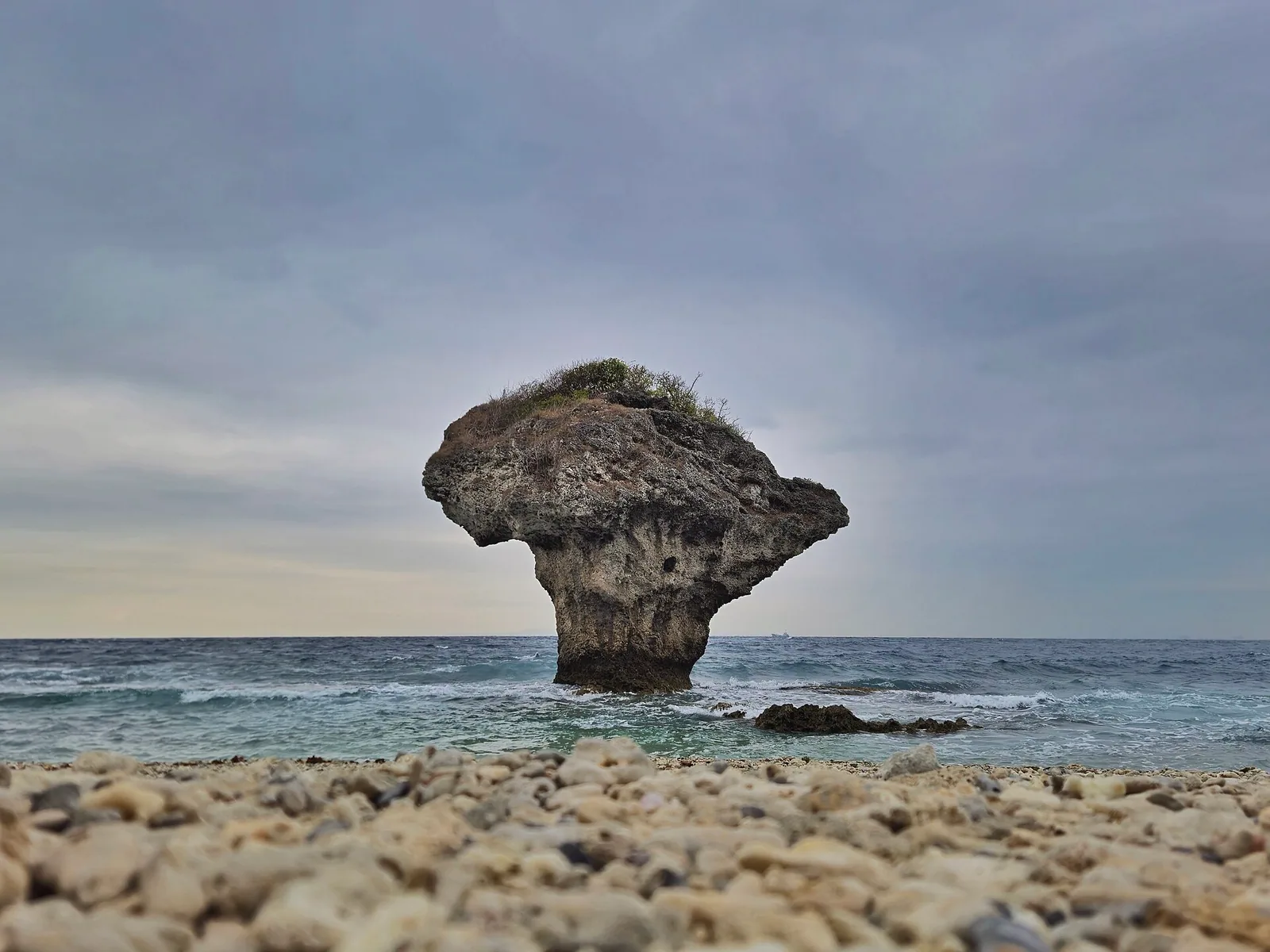 小琉球海岸上的花瓶岩，前景是珊瑚礁碎石與海浪